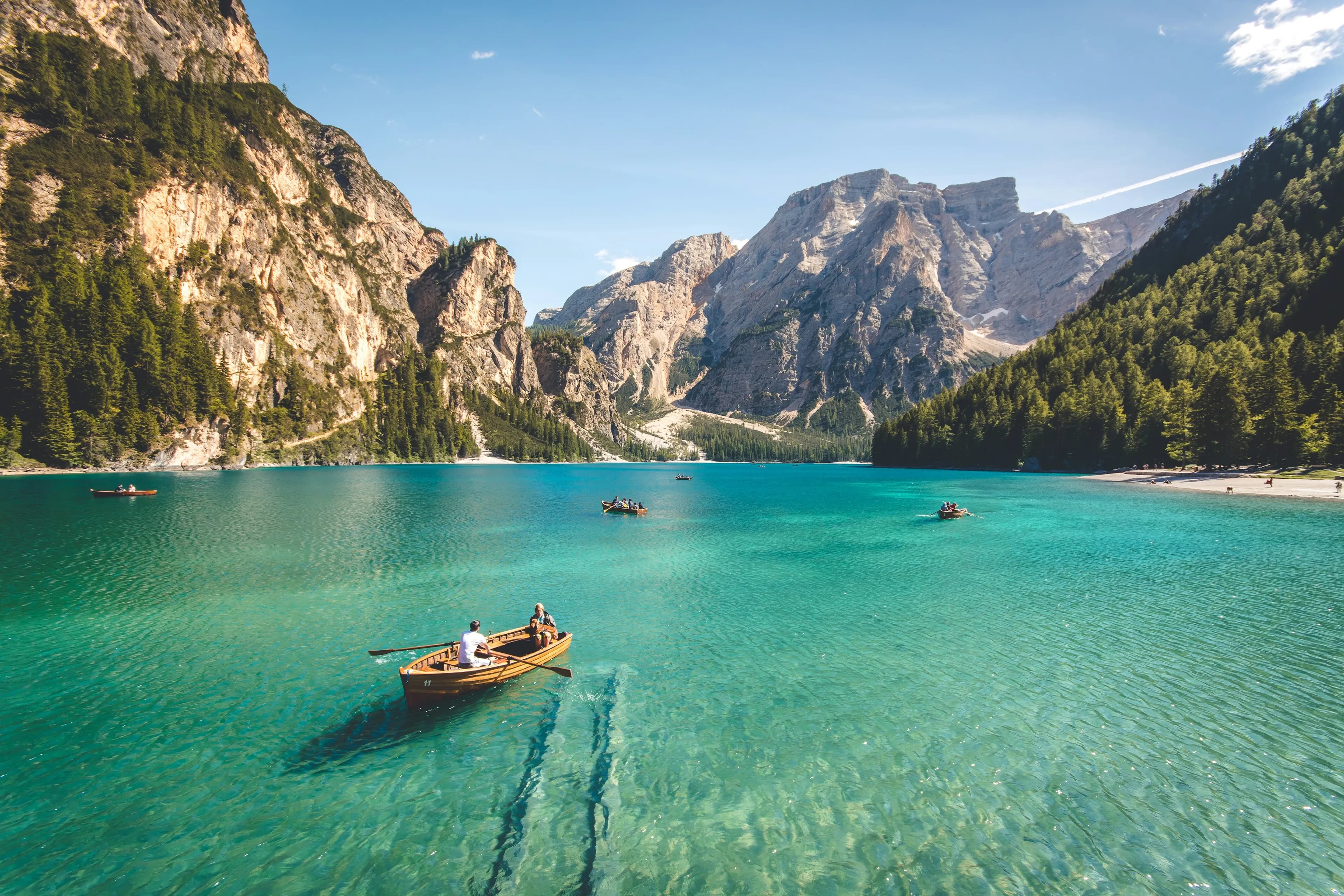 A rowing boat crossing a turquoise alpine lake under limestone walls