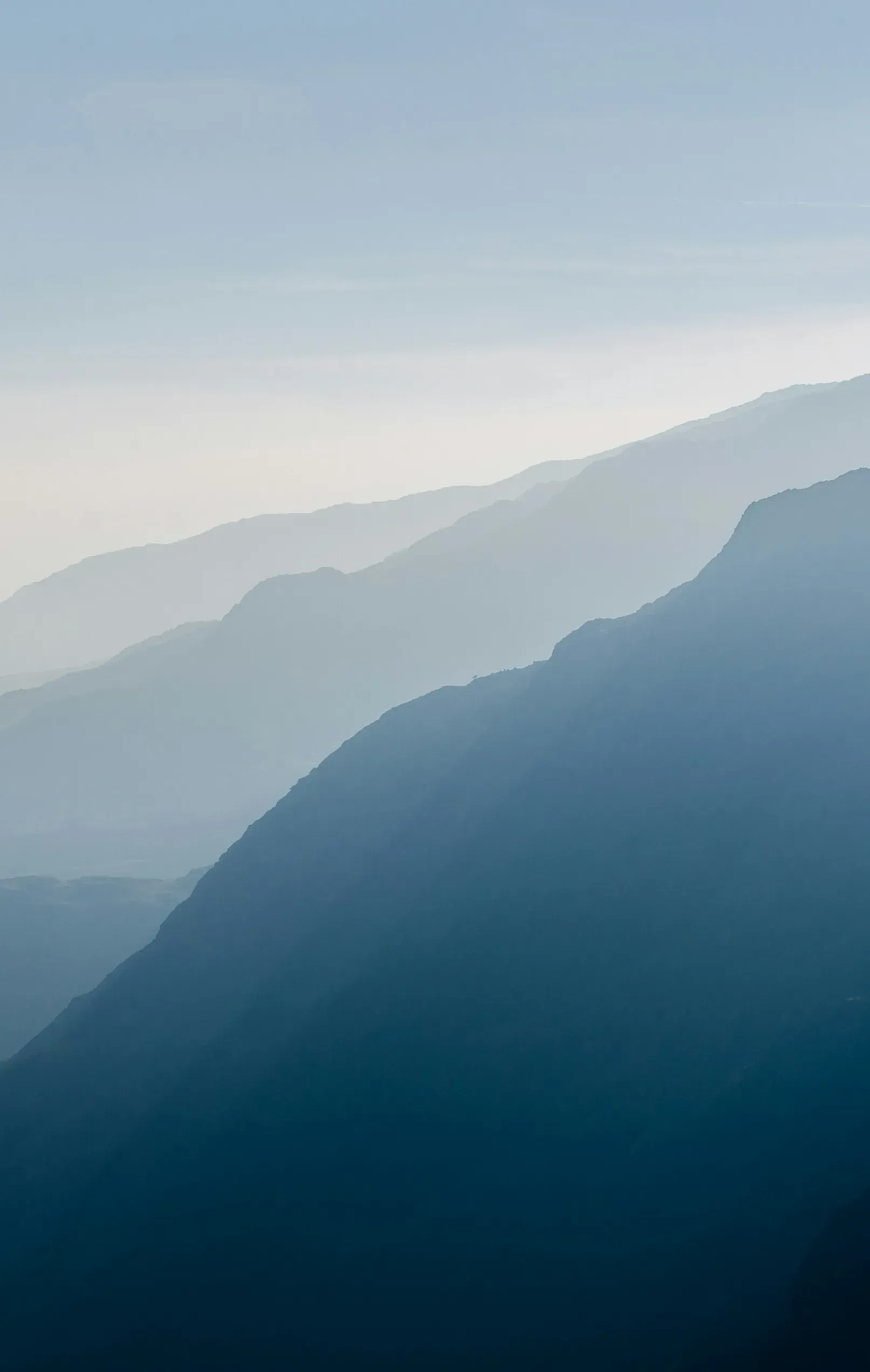 Ridge behind ridge fading into blue haze above a deep alpine valley