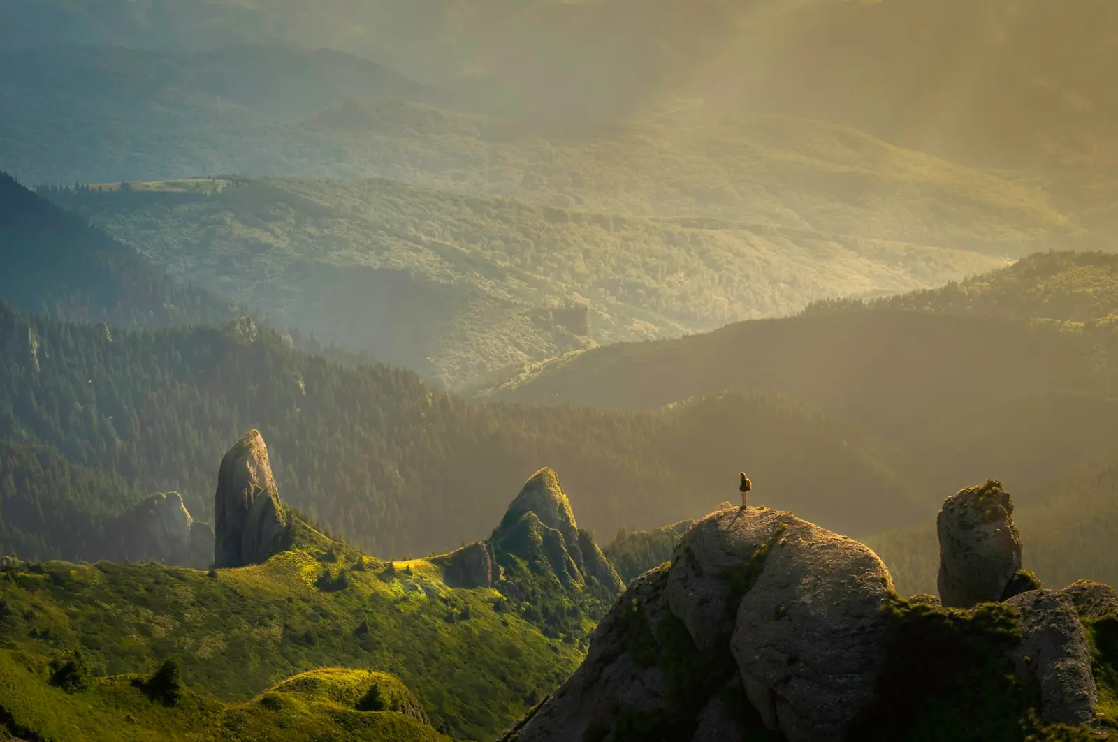 Golden evening light across green ridges and rock towers