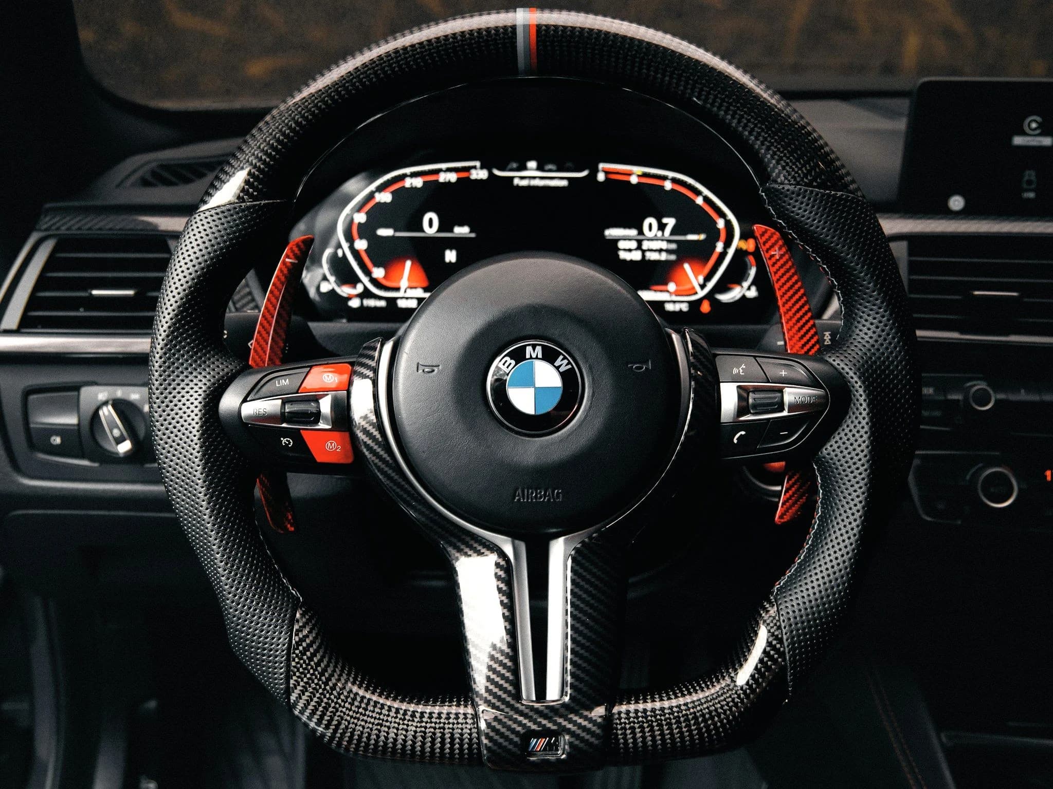 The carbon fibre steering wheel and lit digital instrument cluster of a BMW M car