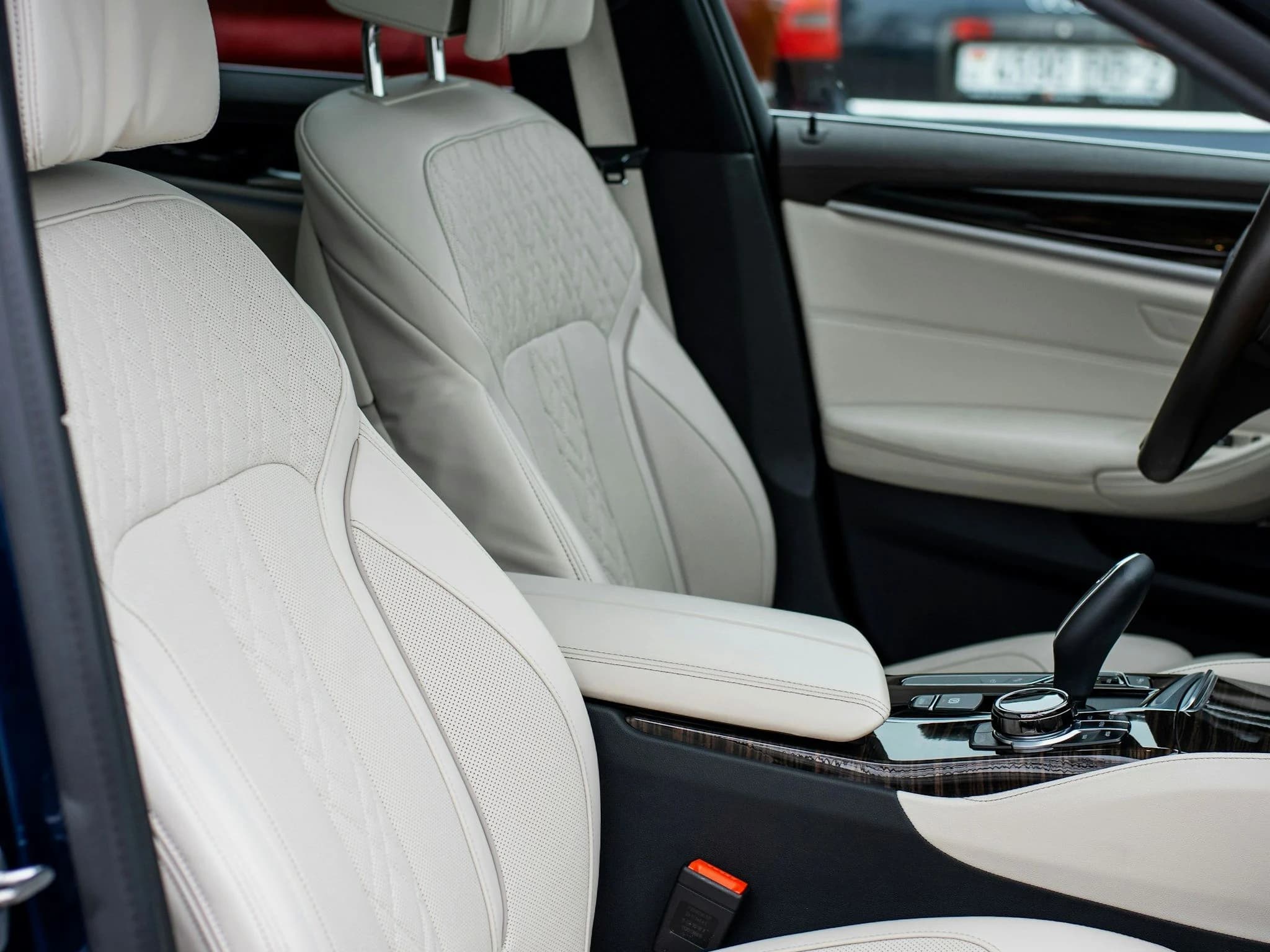 The white leather front seats and centre console of a car interior in daylight
