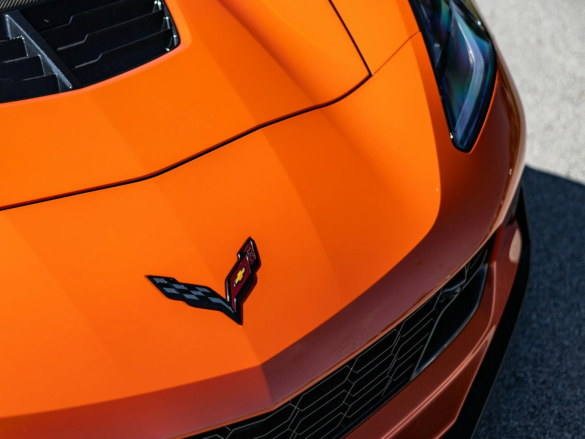 The crossed-flags Corvette badge on the bonnet of an orange car