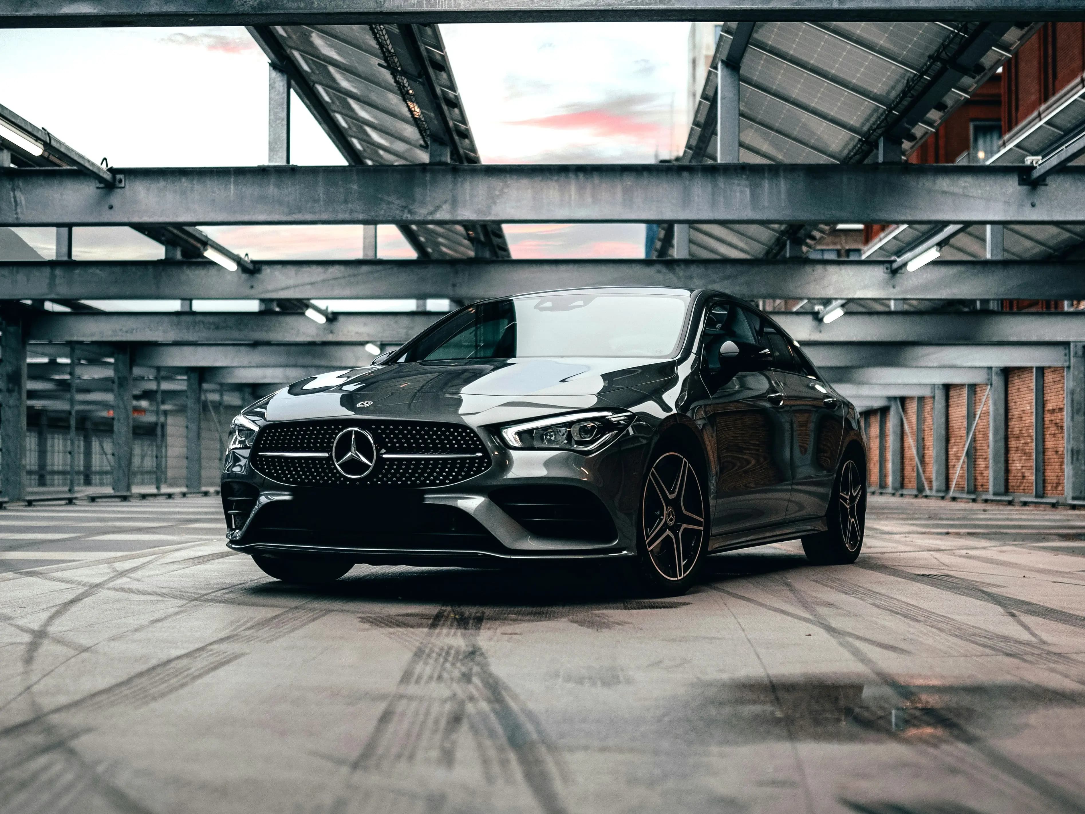 A dark Mercedes coupe parked alone under the concrete deck of a multi-storey car park