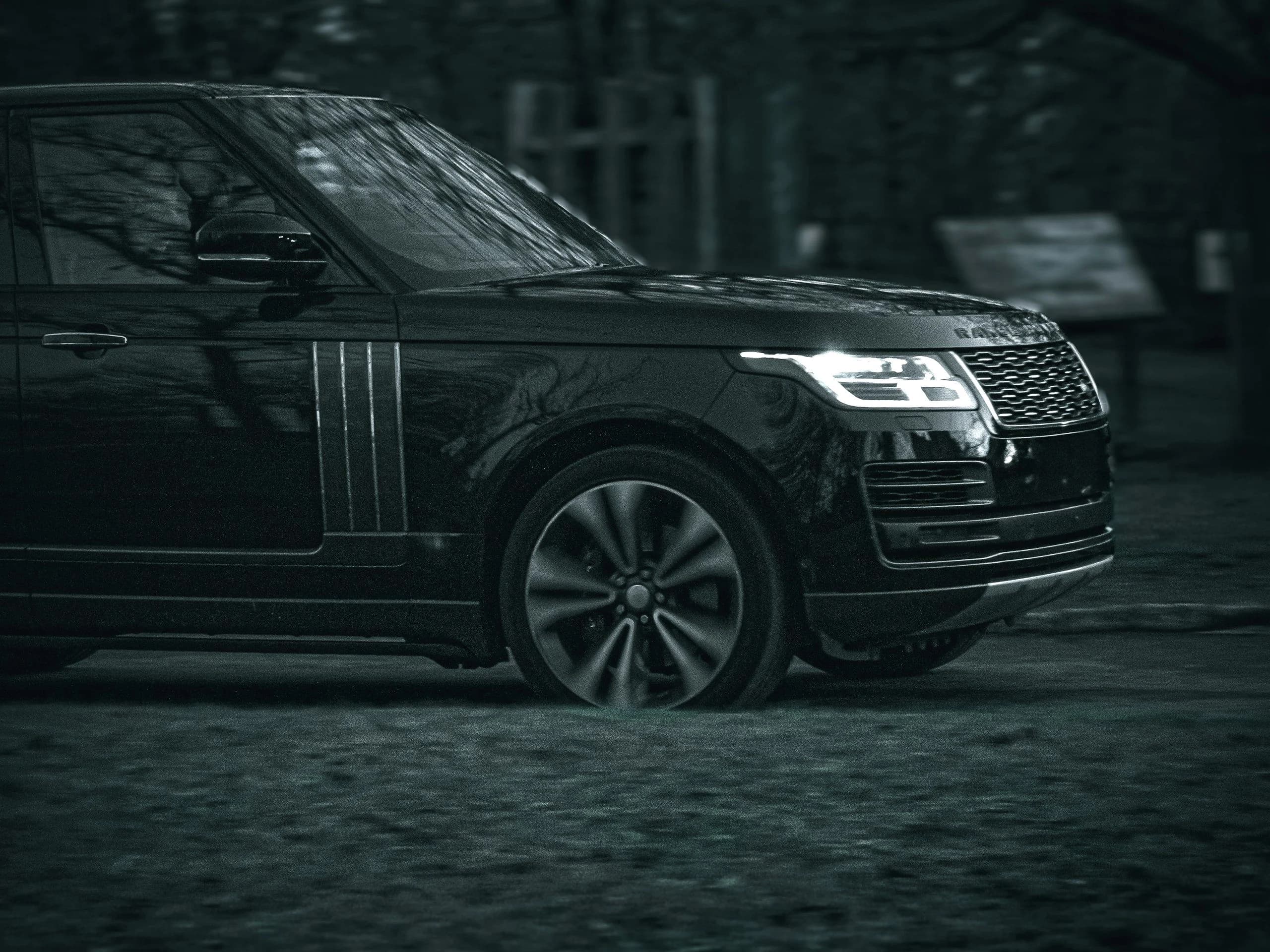 A black Range Rover Autobiography in front-three-quarter view on a dark street, RANGE ROVER lettering visible across the bonnet