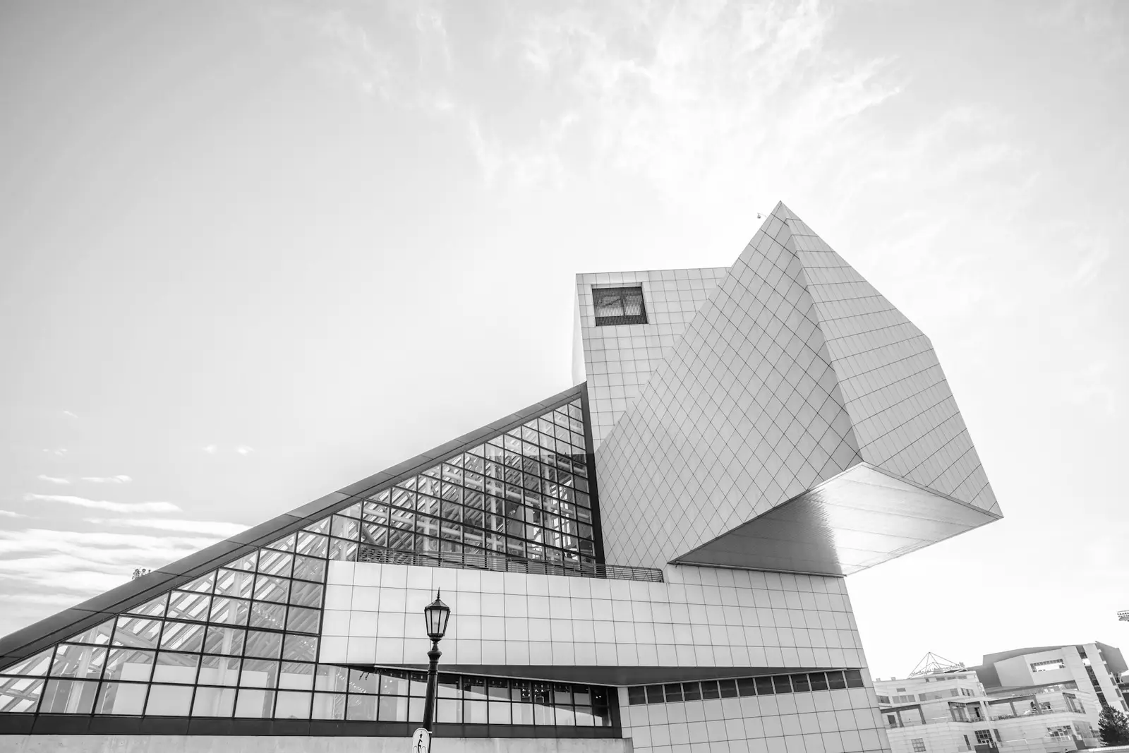 Monochrome photograph of an angular white museum building photographed from below against a bright sky