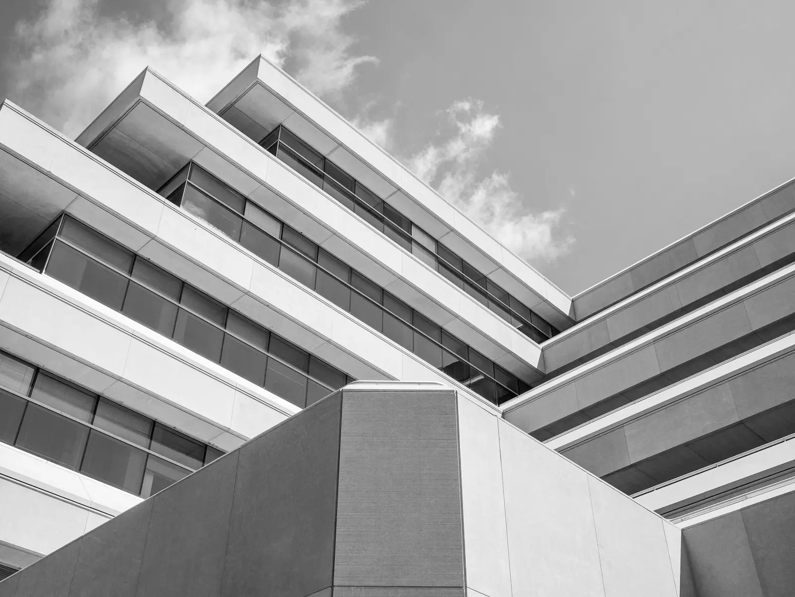 Monochrome photograph looking up at stepped cantilevered concrete floor slabs of a terraced building
