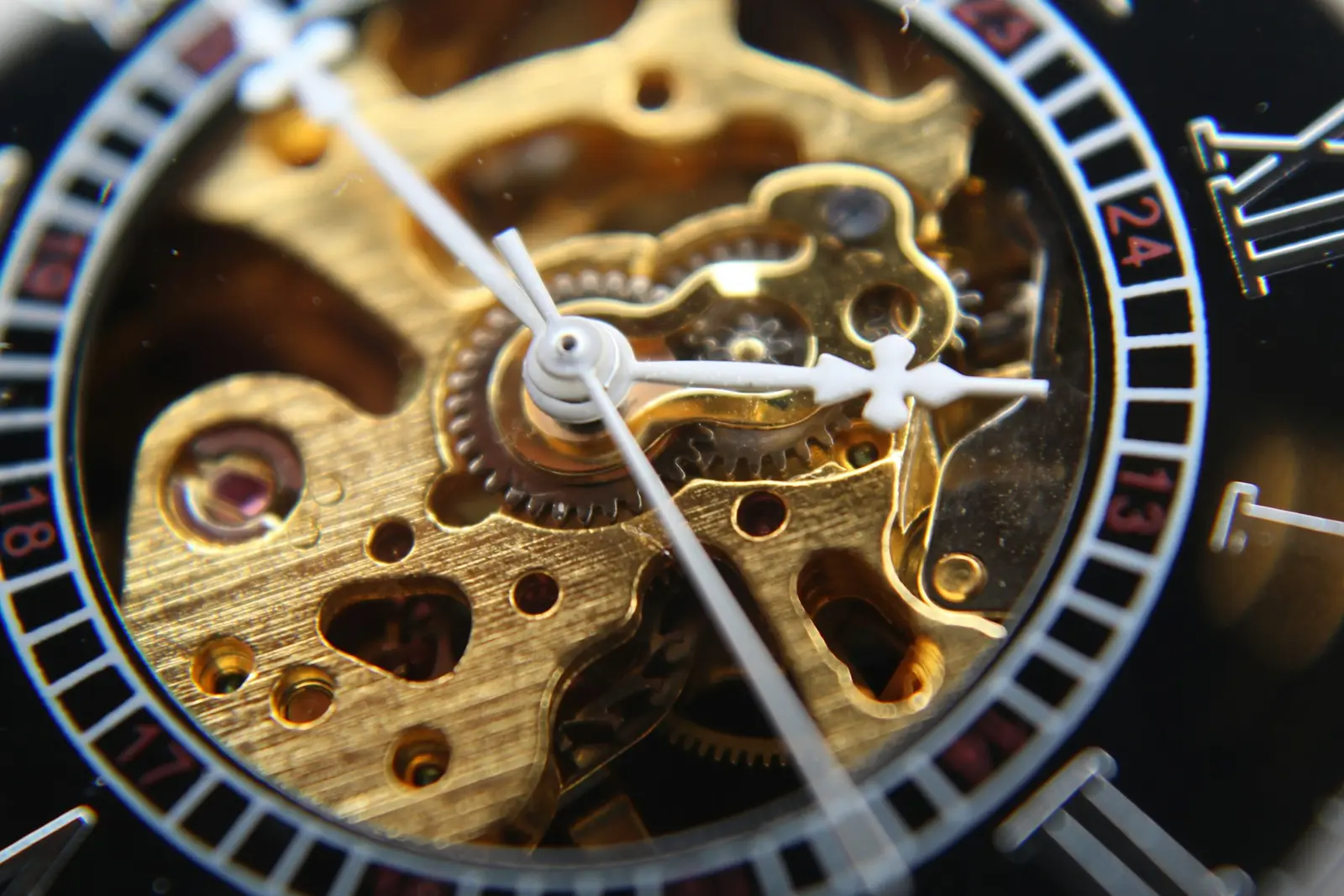 Macro of an openworked MERIDIAN movement behind its crystal: gilded plates, roman numerals, polished hands