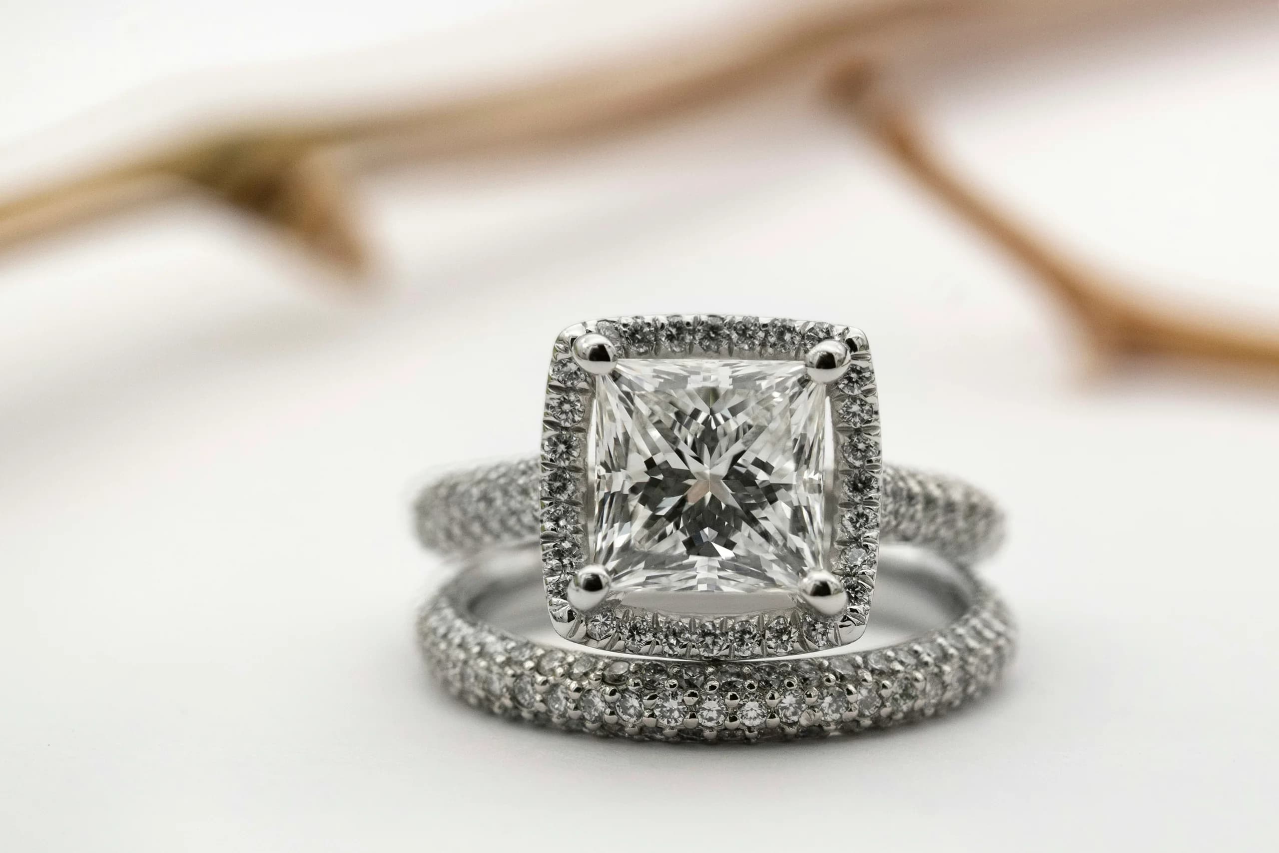 A cushion-cut halo ring standing in its pavé wedding band, photographed on white