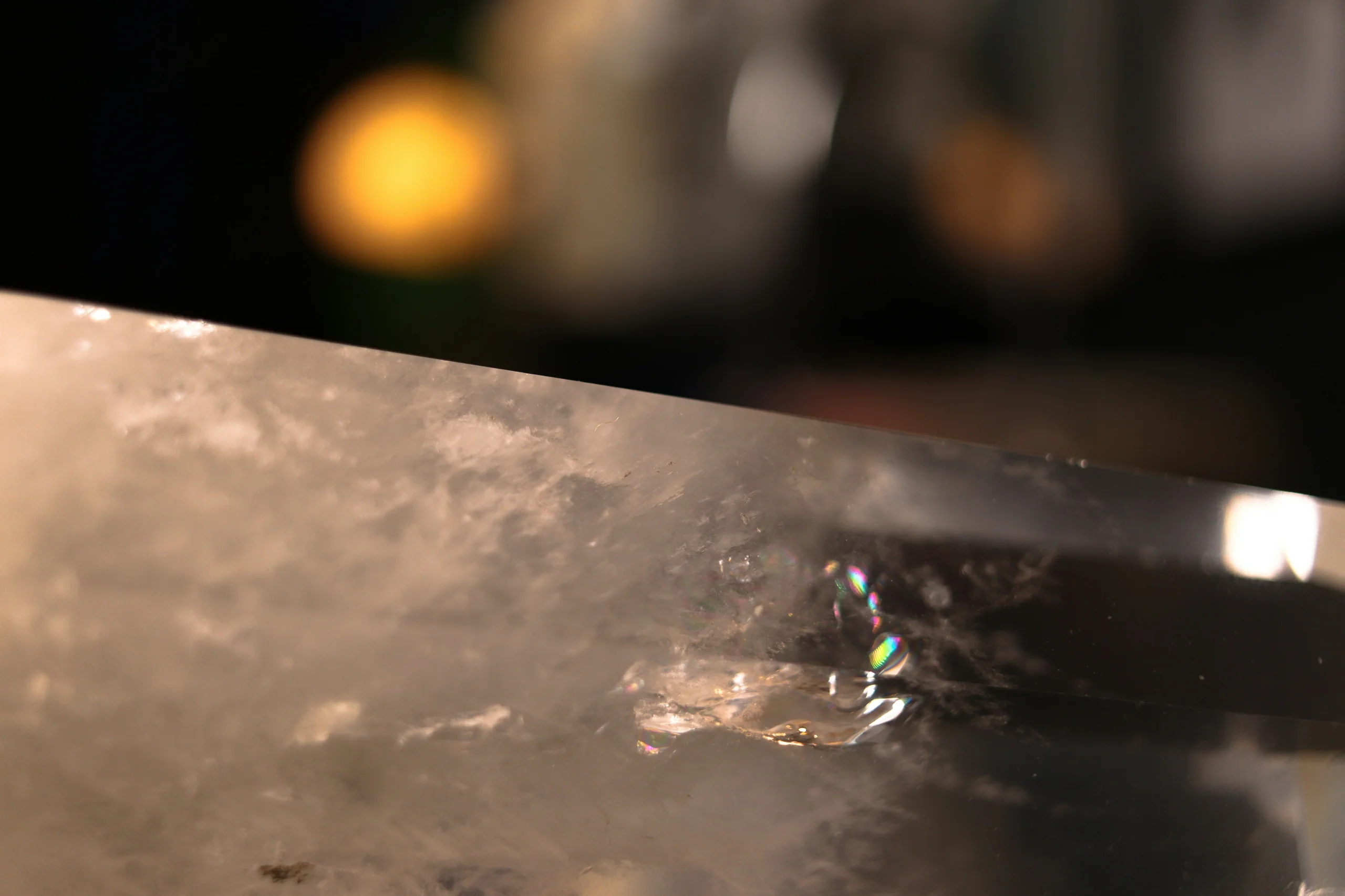 Macro of the edge of a clear quartz block on the light table, a rainbow flash inside it