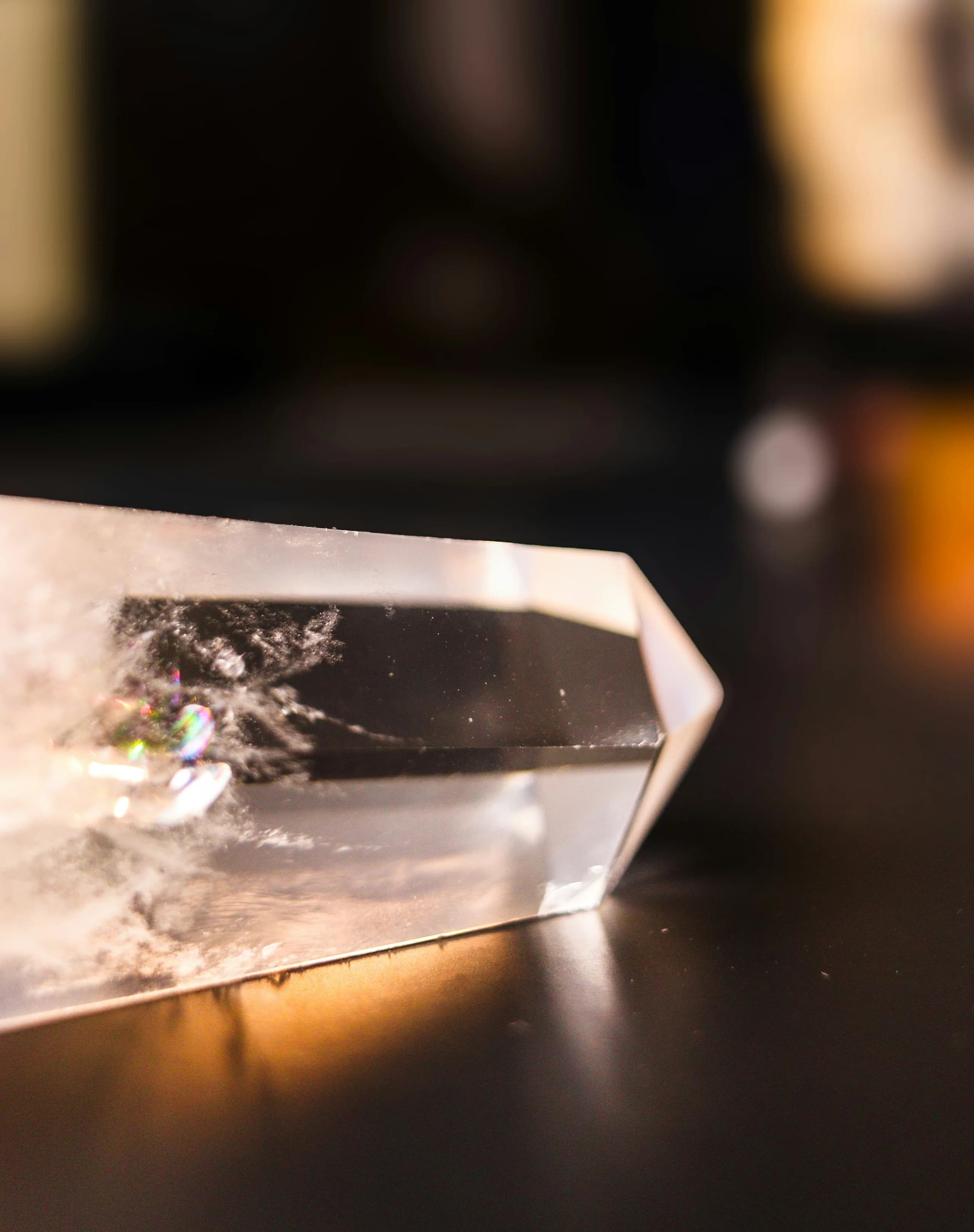A polished quartz point lying on the dark sorting table with a warm lamp behind it