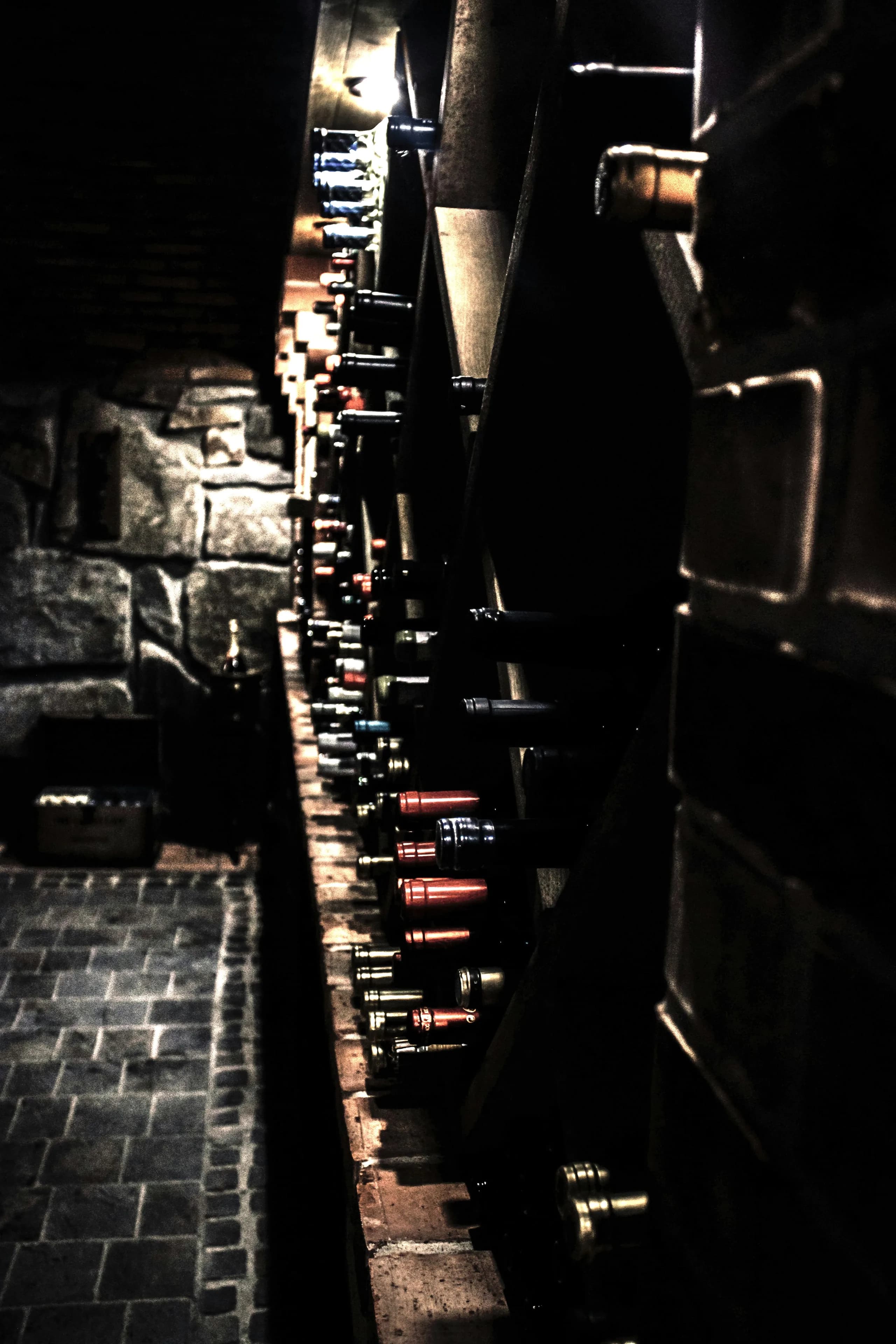 Wine bottles resting on their sides in the racks of a dark stone cellar