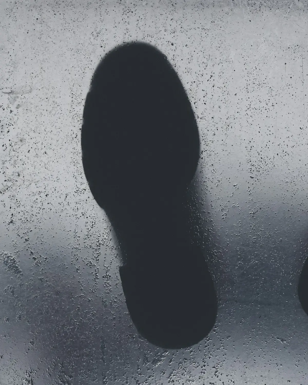 A single blank insole silhouette on speckled grey concrete