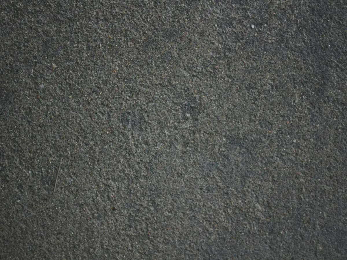 Coarse dark grey asphalt seen close, flecked with pale aggregate.