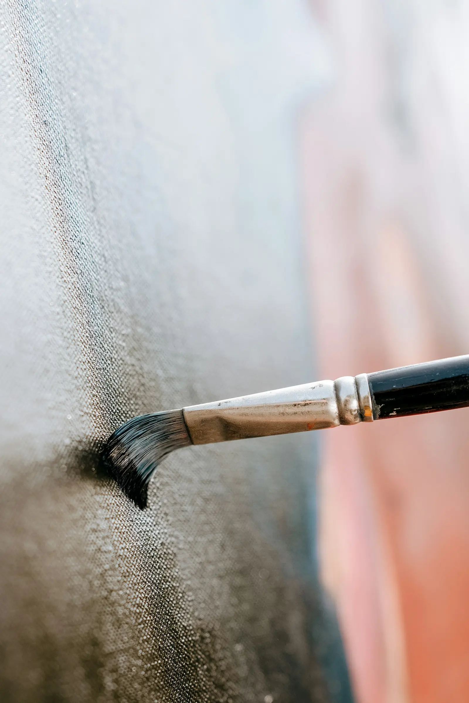 Fine brush pressed into a textured wall, cutting a clean dark line