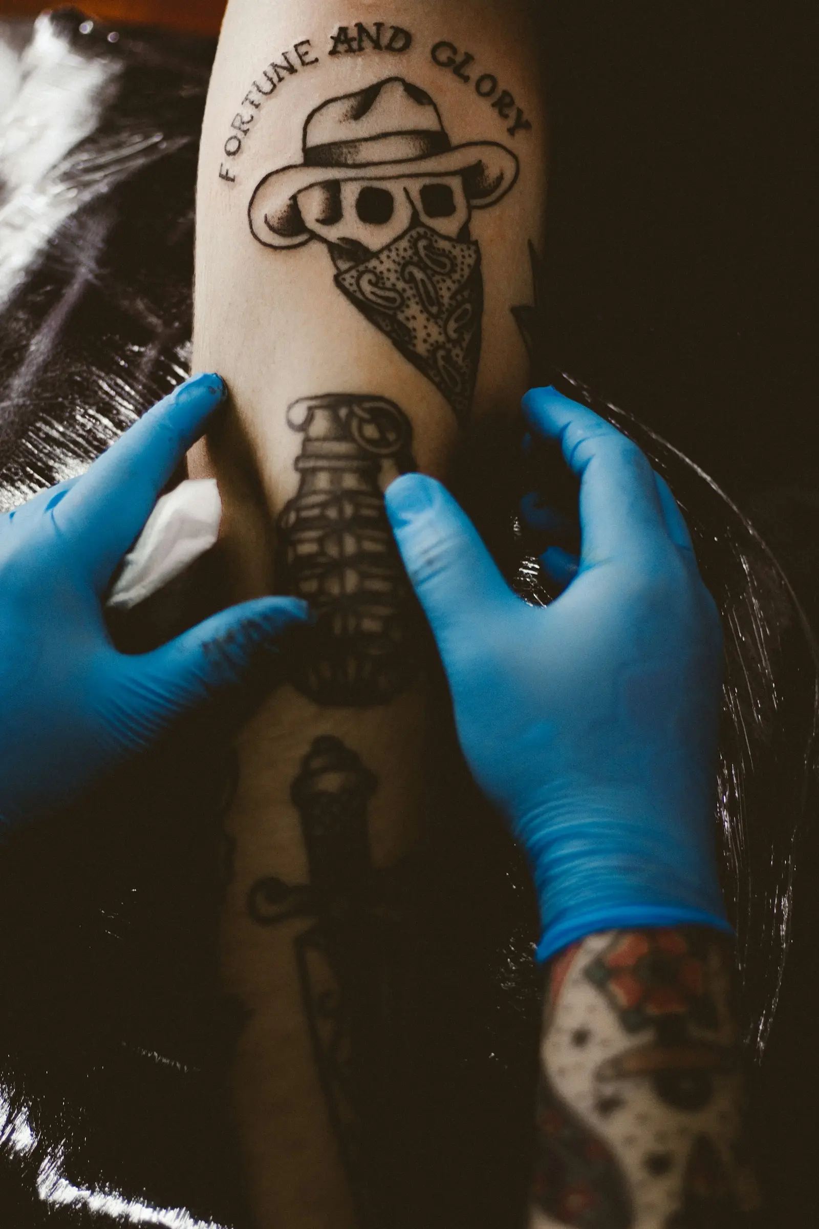 Fortune and glory script tattoo with a bandit skull on a forearm