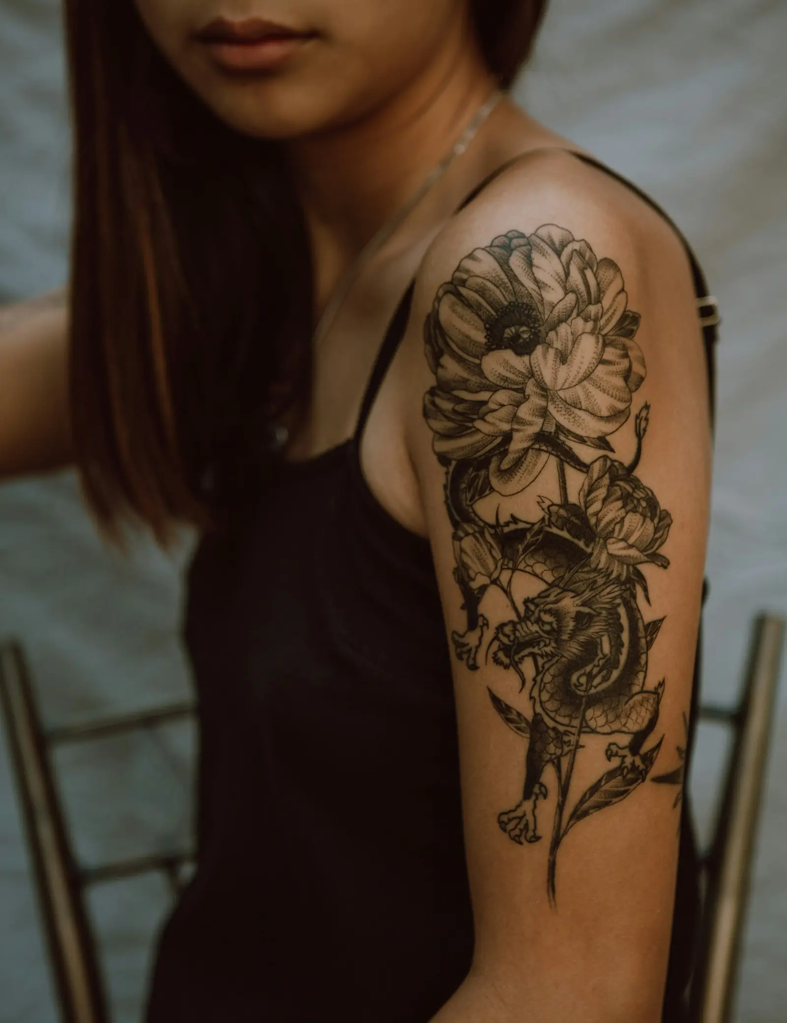 Blackwork floral and dragon piece across a shoulder