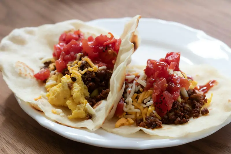 Flour-tortilla breakfast tacos with scrambled egg, chorizo, cheese, and salsa