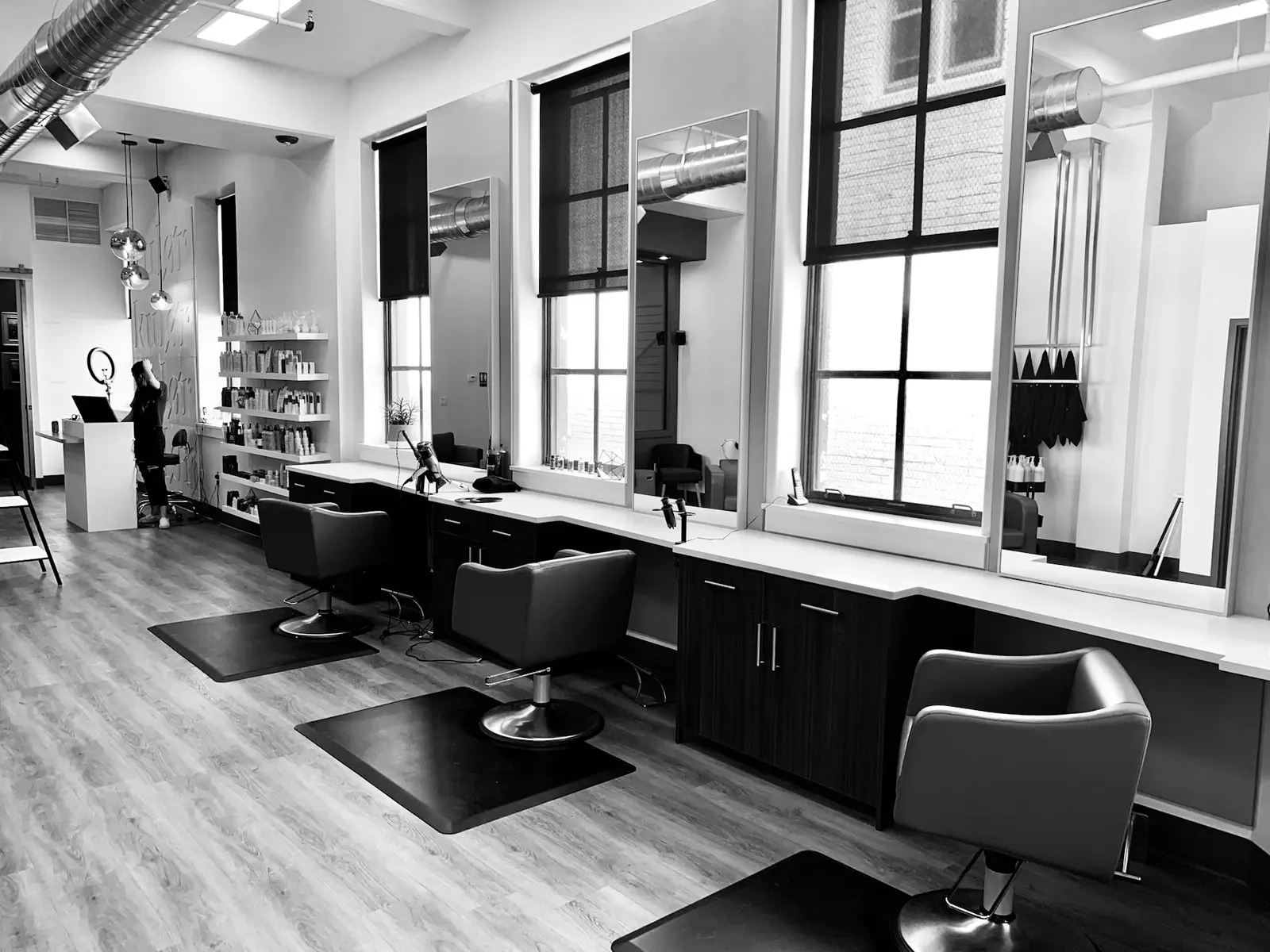 Salon stations in black and white — chairs, mirrors and tall windows