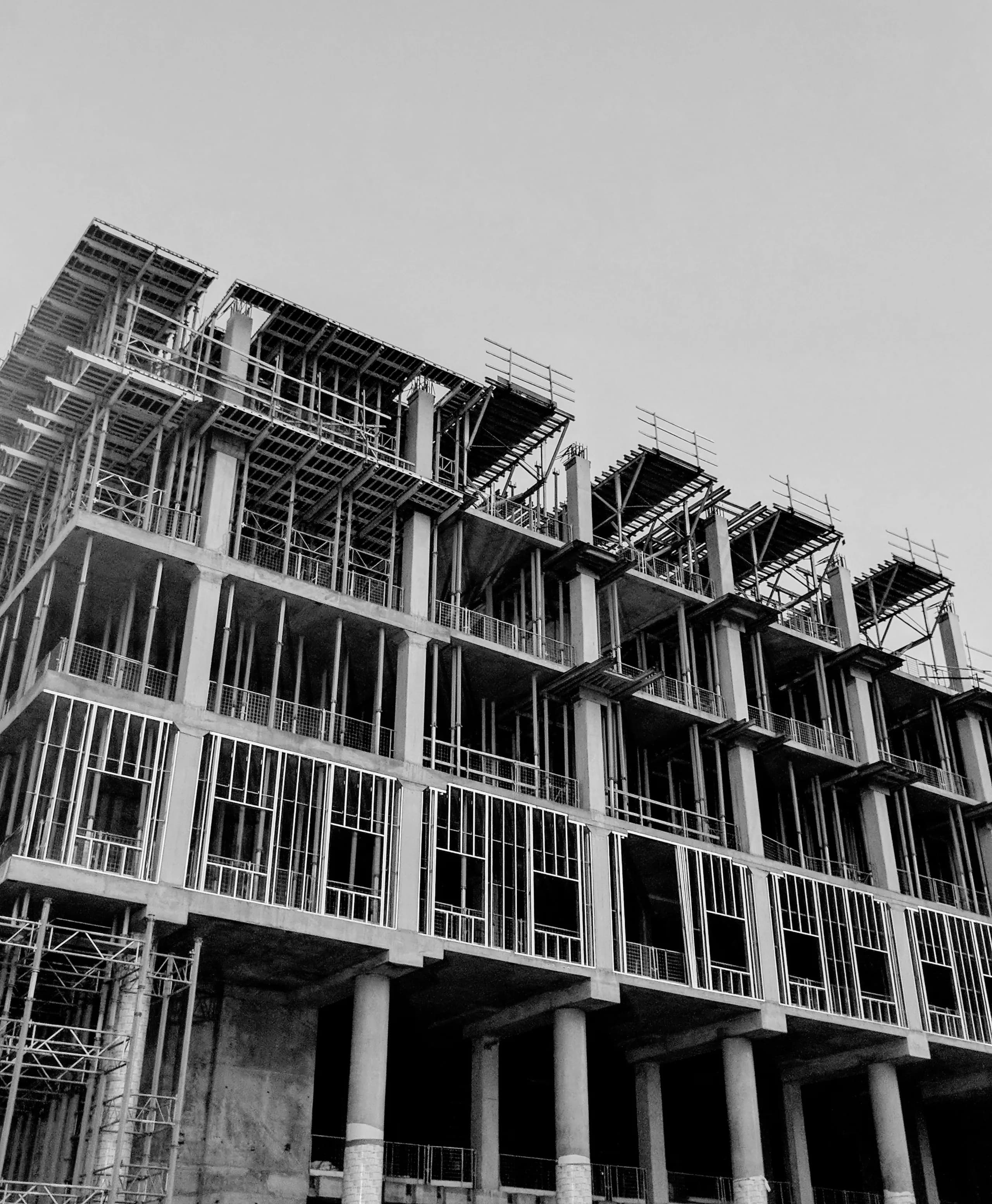Monochrome detail of a concrete frame with formwork against a pale sky