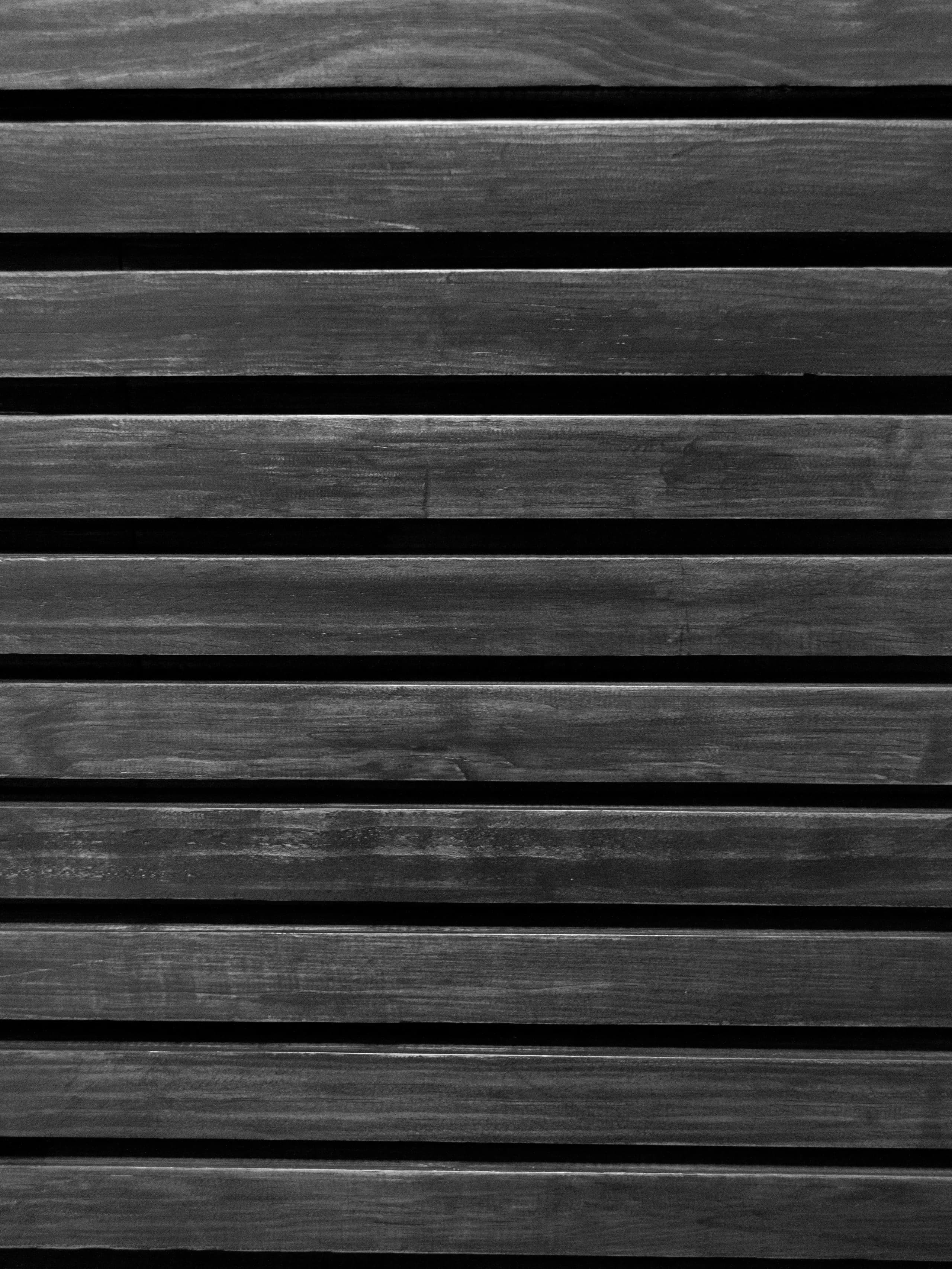 Monochrome detail of charred timber slats with shadow gaps