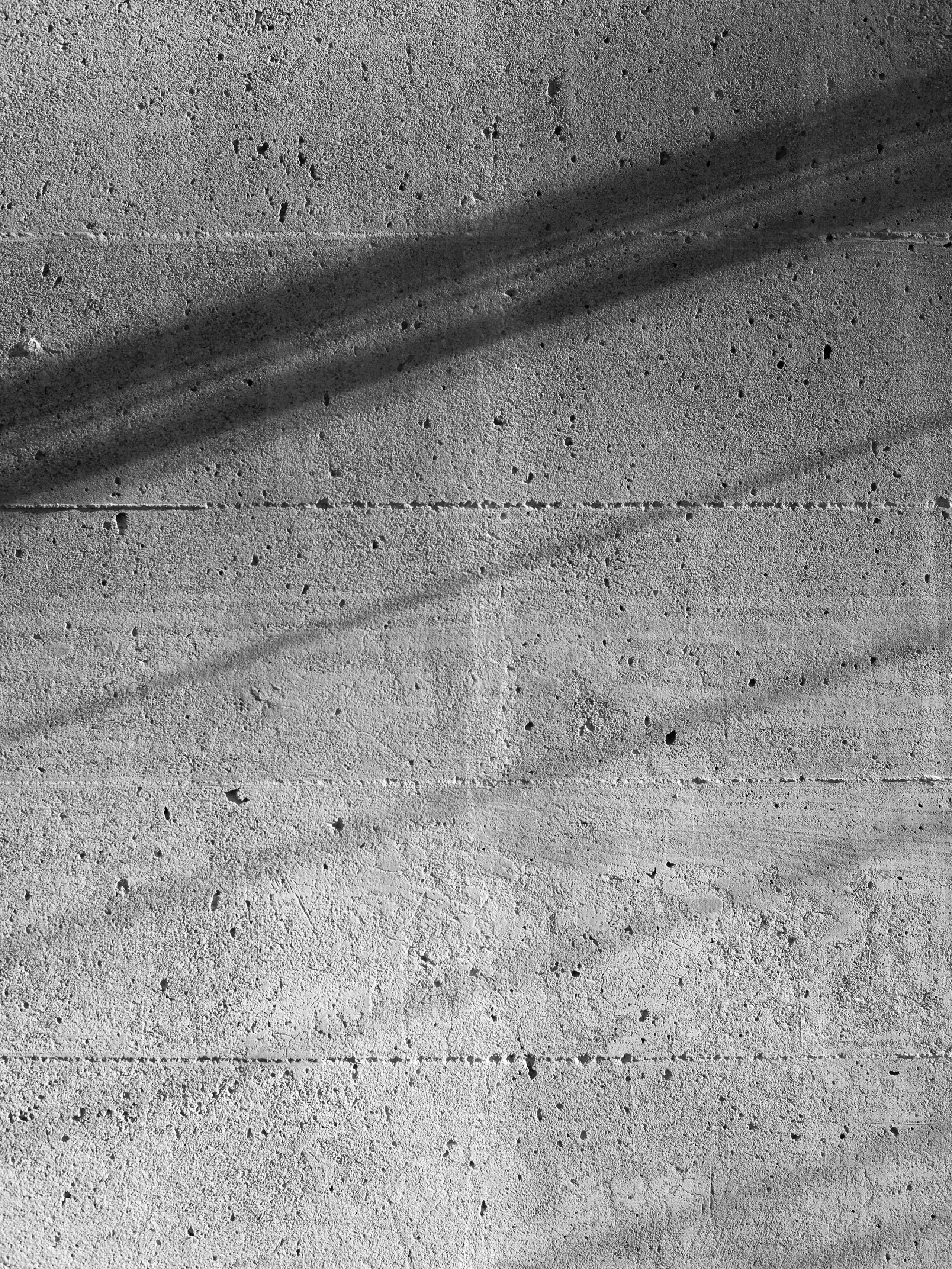 Monochrome detail of board-formed concrete with shutter lines and tie holes