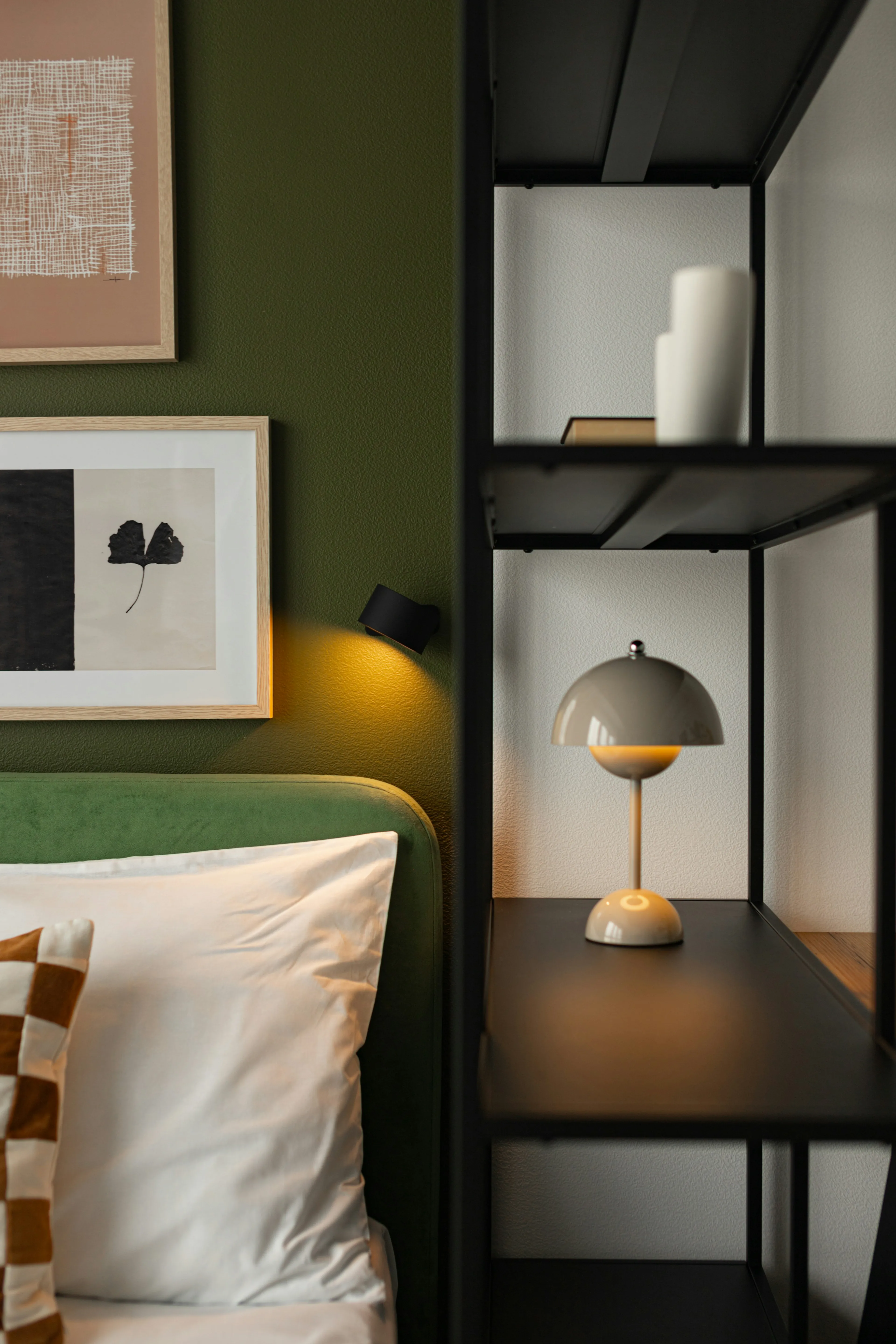 A bedroom corner with a deep green wall, framed prints and a warm lamp, washed back behind the quote